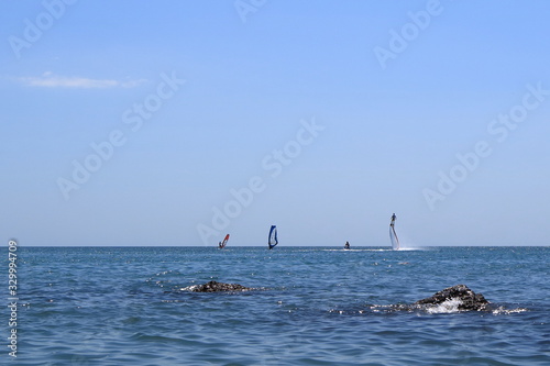 Walk on the sea on a board with a sail. Flying on a water jet.
