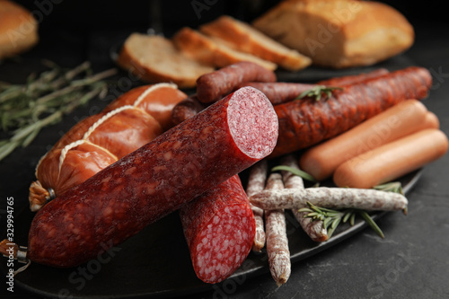 Fotografija Different tasty sausages on black table, closeup