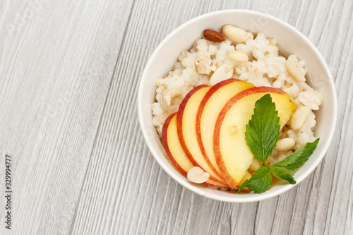 Sorghum salad with nuts and fresh peach on wooden background.
