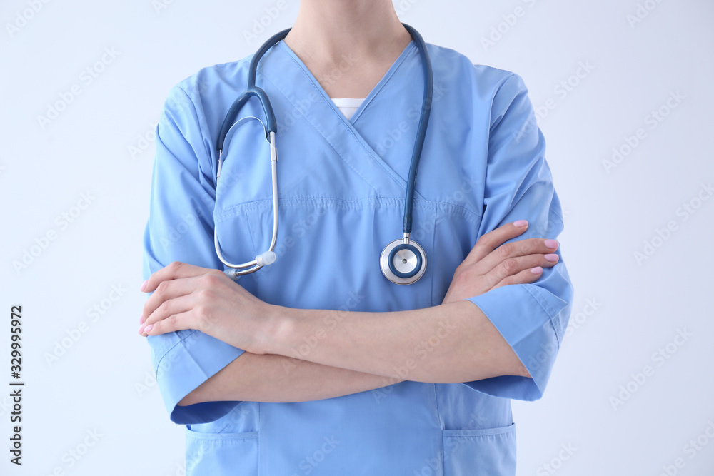 Young doctor with stethoscope on light background, closeup Young doctor with stethoscope on light background, closeup