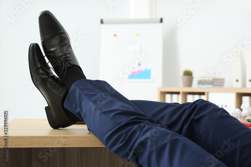 Lazy office employee resting with feet up on desk at workplace, closeup