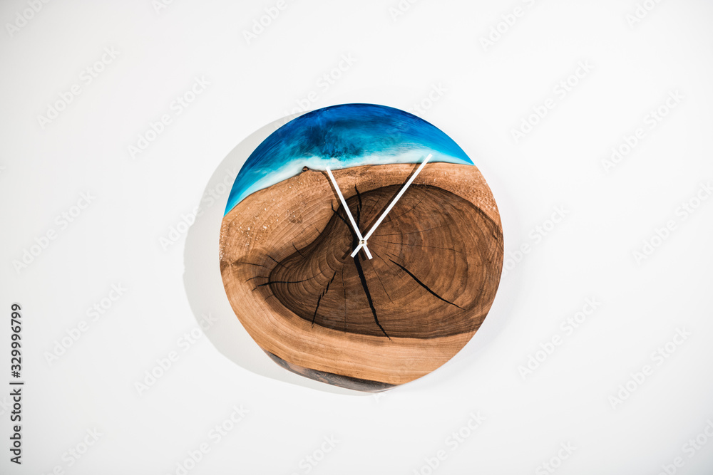 Round eco clock made of wood and epoxy. The subject of interior in your home. Natural handmade tree. Clock isolated on white background.