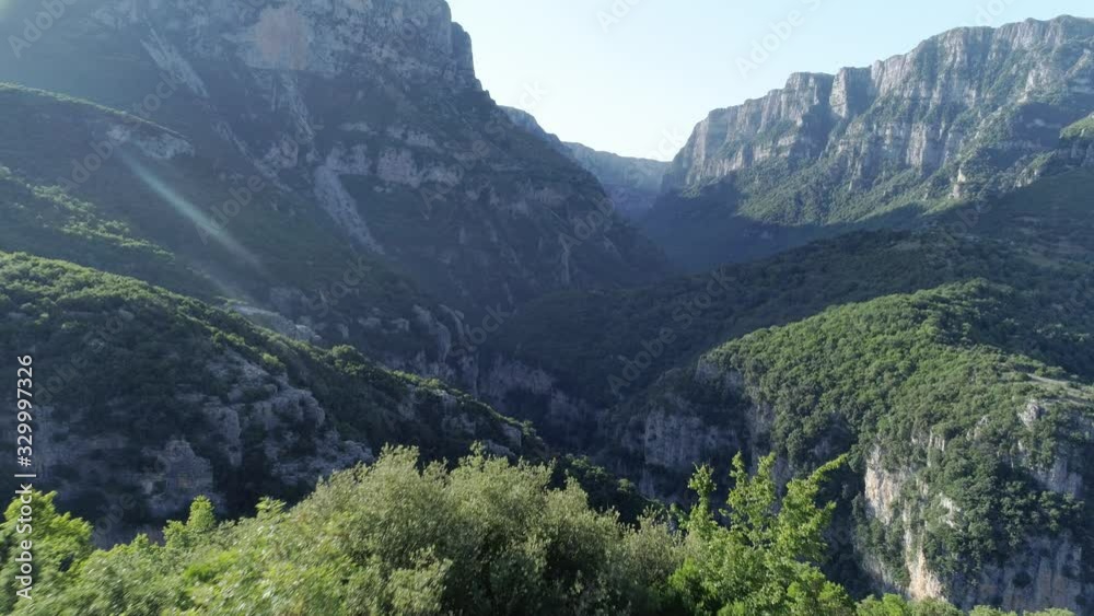 Aerial view passing over girl sitting on a bench going towards impressive Vikos Gorge in Epirus, Greece, drone Aerial view passing over girl sitting on a bench going towards impressive Vikos Gorge in Epirus, Greece, drone
