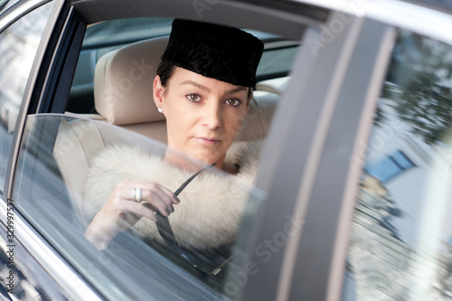 Luxury woman with fur and sunglasses in the back seat of a car