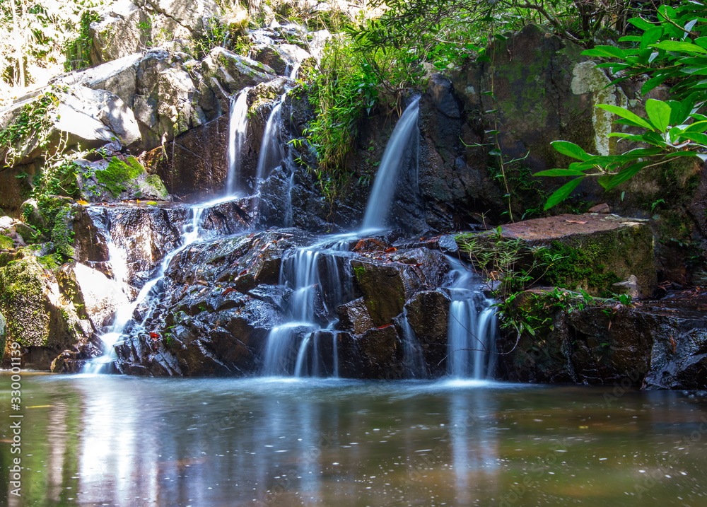 Fototapeta premium Water flows down the rocks. Waterfall in a park.