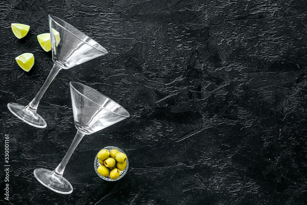 Aperitif drink concept. Martini glasses near olives and lemon on black background copy space
