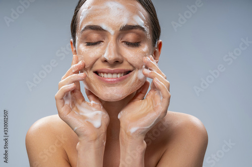 Behang Young pretty lady washing her face with soap