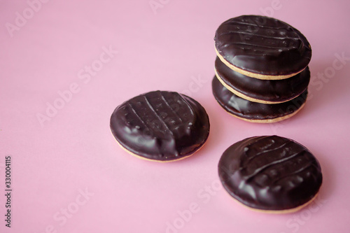 A pile of Jaffa cakes. Cookies covered with dark chocolate and filled with pink strawberry or cherry marmalade. Delicious biscuits isolated on pink background with copyspace