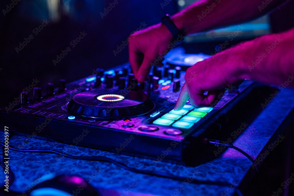 Obraz premium hands of a DJ playing music on a mixer at a concert
