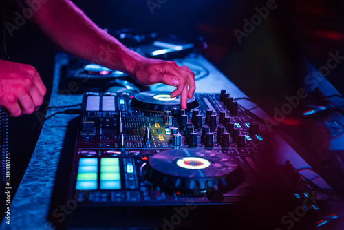 hands of a DJ mixing music on a professional controller in a booth