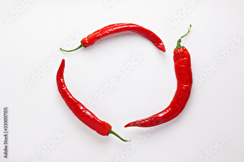 Red chili peppers on white  wood background. Hot spicy food ingredient. Circle frame. Top view photo