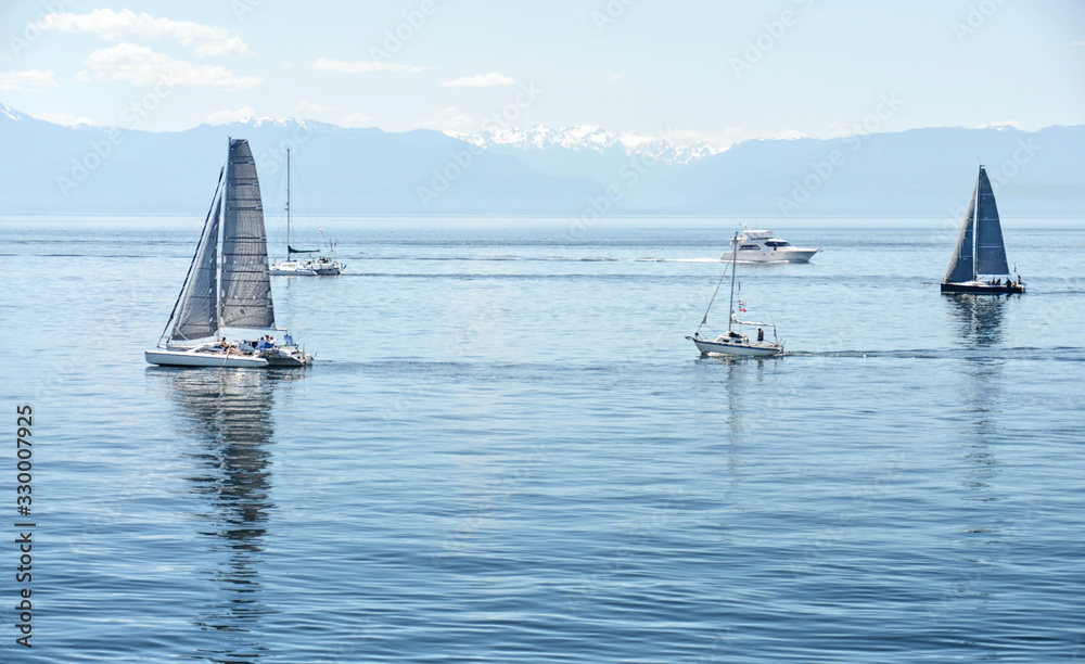 Obraz premium yachts and catamarans in sailing races in sunny summer day. regatta is starting: sailboats go away to the Pacific ocean. Victoria, British Columbia. Canada