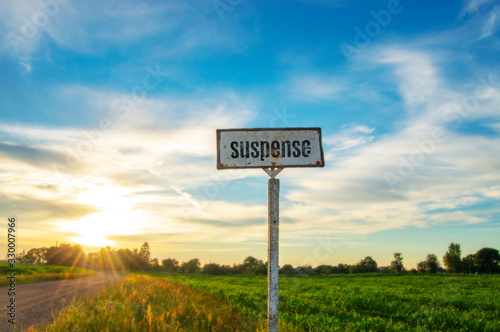 Old road sign in the countryside at sunset and the text "suspense".