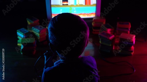 Little boy playing in retro console. Neon lighting.A view from the shoulders