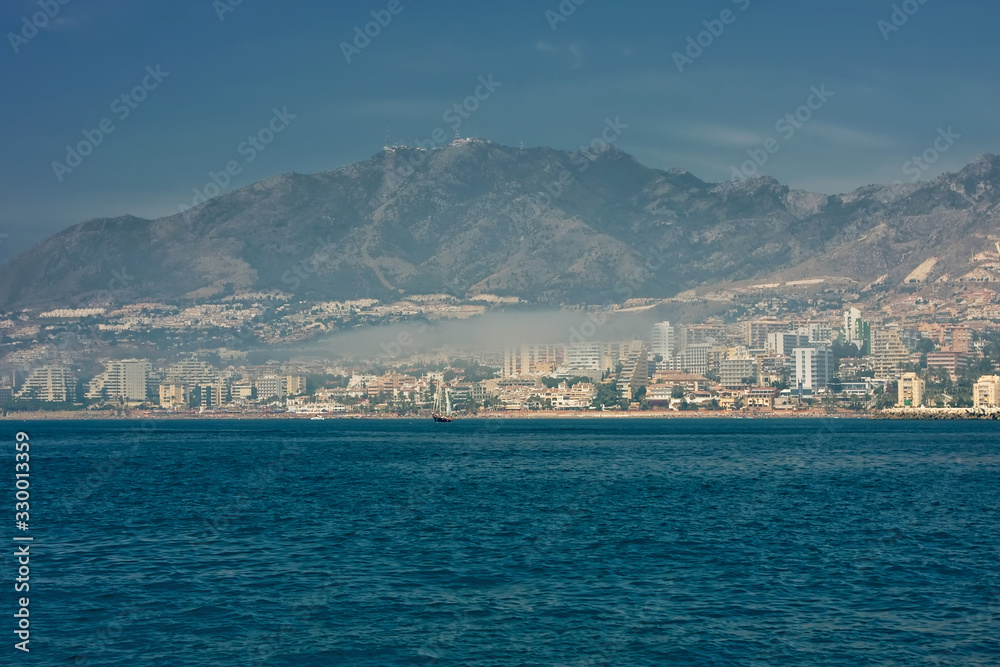 The blue sea, the city, followed by mountains and fog