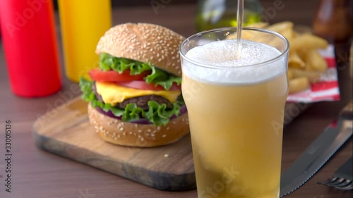 pouring cold beer into glass with chees burger background