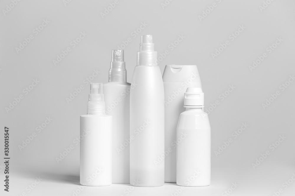 Set of cosmetic products in white and grey containers on light background. Set of cosmetic products in white and grey containers on light background.