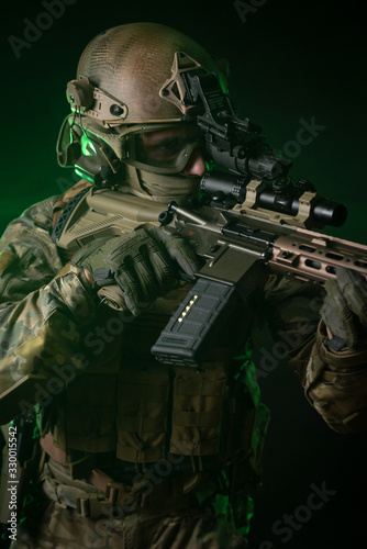 a soldier in military clothing with a night vision device and on a dark background photo