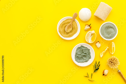 Face, body skin care homemade ingredients - cosmetic clay, brushes, homemade soap, scrub, herbs on a yellow background - top view