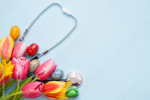 Photography Stethoscope with colorful eggs and tulips on a blue background