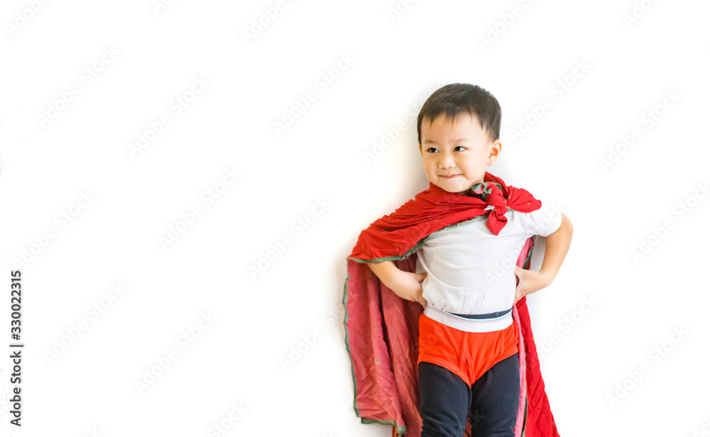 Handsome little asian toddler boy jumping posting from sofa couch to ready to fight and fly when he play as superhero with cloak and red shot paint at home in living room.isolated on white background. Handsome little asian toddler boy jumping posting from sofa couch to ready to fight and fly when he play as superhero with cloak and red shot paint at home in living room.isolated on white background.