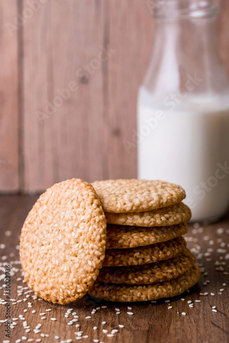 Round sesame cookies with milk and juice on the table.