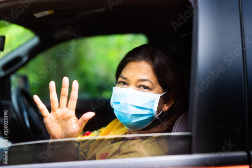 Covid-19 virus and Coronavirus concept.Senior old woman wearing mask for protect virus and waving hand in car. Covid-19 virus outbreak.Indian old woman and coronavirus.Epidemic virus symptoms.