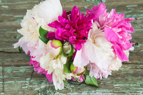 Bouquet of purple  white and pink peonies on old paint wooden background close up