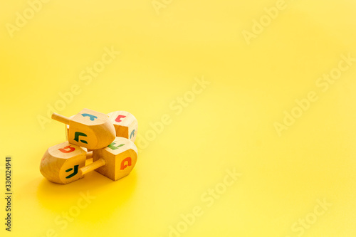 Hanukkah dreidels on yellow table. Jewish holideys concept. Close up, space for text photo