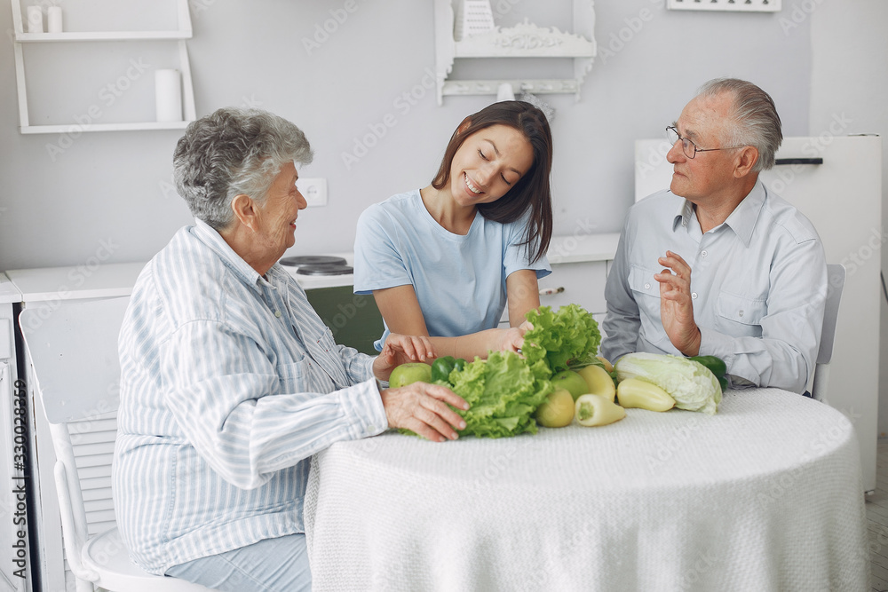 Family in a kitchen. Grandparents with granddaughter. Family made a salad Family in a kitchen. Grandparents with granddaughter. Family made a salad