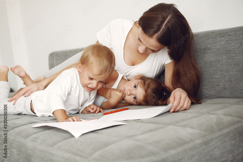 Cute family in a room. Lady in a white shirt. Mother with cute children Cute family in a room. Lady in a white shirt. Mother with cute children