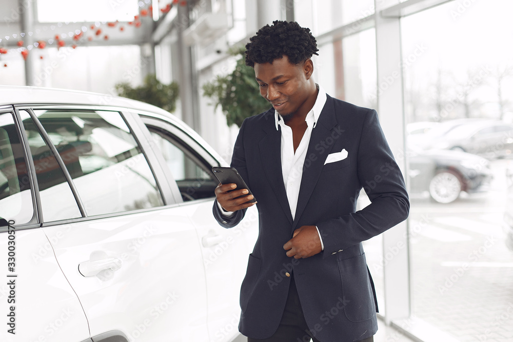 Man buying the car. Businessman in a car salon. Black male in a suit. Man buying the car. Businessman in a car salon. Black male in a suit.