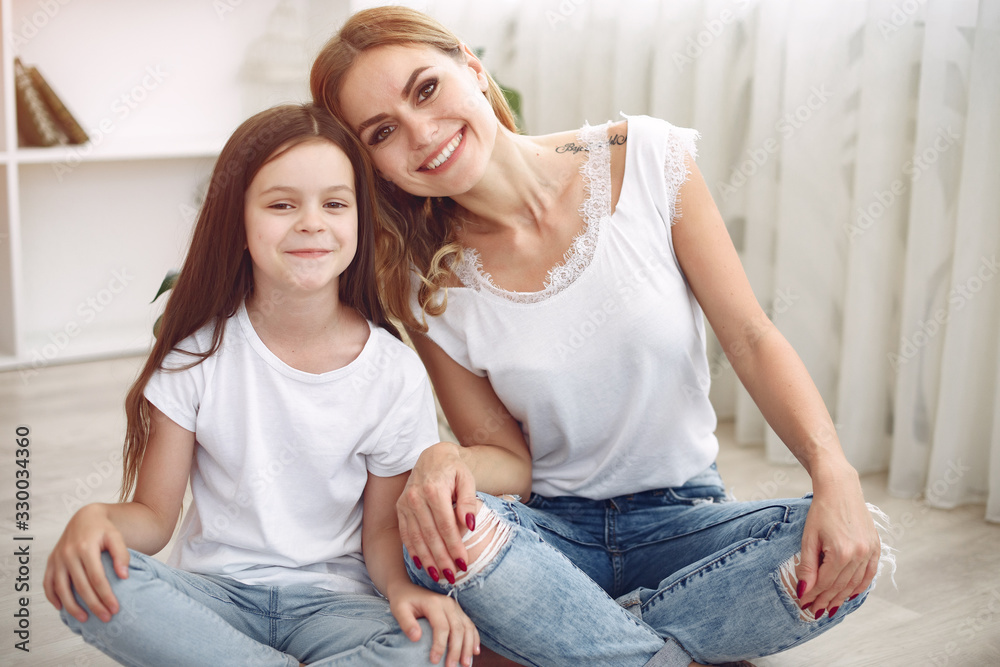Beautiful woman with child. Woman in a white t-shirt. Little daughter in a bedroom Beautiful woman with child. Woman in a white t-shirt. Little daughter in a bedroom