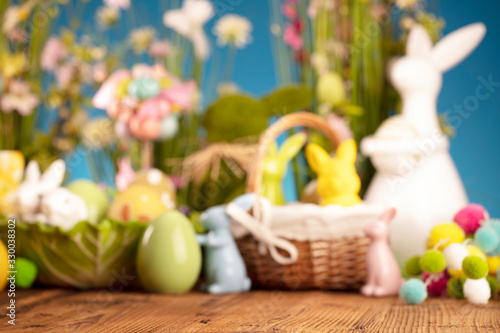 Happy Easter background. Bouquet of spring flowers. Easter decorations and Easter eggs in basket on rustic wooden table.