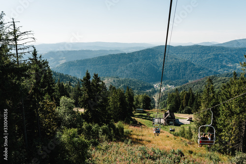 Family rides on a ski lift in the mountains. Mom, dad and girl in mountains in nature. The concept of summer holiday.