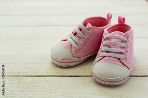 Pink baby girl shoes, on gray background. Newborn, motherhood, pregnancy concept with copy space.