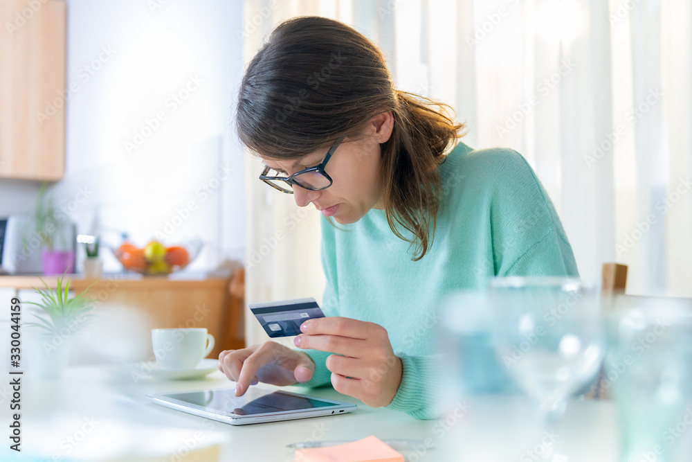 Young modern woman is entering credit card data on her laptop in her home. Young modern woman is entering credit card data on her laptop in her home.