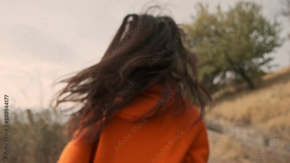 Back view of playful pretty athletic woman in earphones having fun and walking at seashore Back view of playful pretty athletic woman in earphones having fun and walking at seashore
