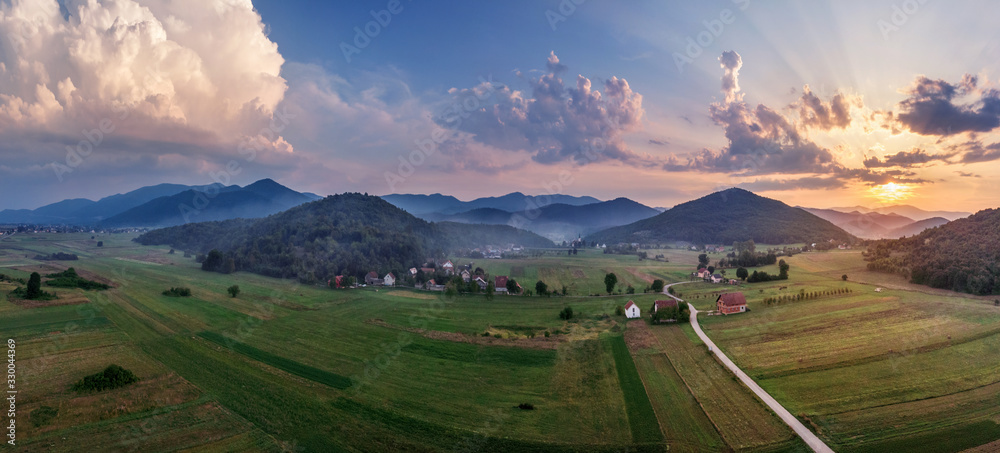 Beautiful sunset in mountains in Croatia. Bird's eye view panorama of amazing sky and the red sun lights shooting clouds over valley.