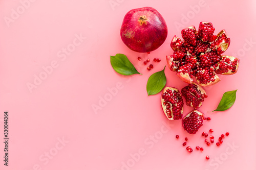 Ripe pomegranate fruit near leaf on pink background top-down copy space photo