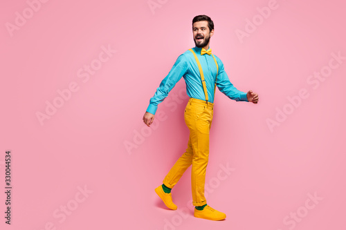 Full length body size view of his he nice attractive cheerful cheery imposing well-dressed guy wearing mint shirt yellow pants clothes walking isolated on pastel pink color background