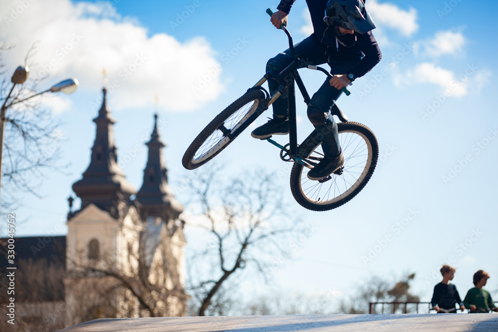 Obraz premium Young man doing tricks on a BMX bike. BMX freestyle against the backdrop of urban landscape. Extreme sports is very popular among youth.