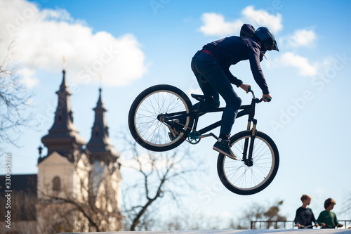 Young man doing tricks on a BMX bike. BMX freestyle against the backdrop of urban landscape. Extreme sports is very popular among youth. © tygrys74