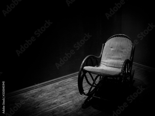 Wicker rocking chair in empty room with wooden floor, monochrome minimalist style