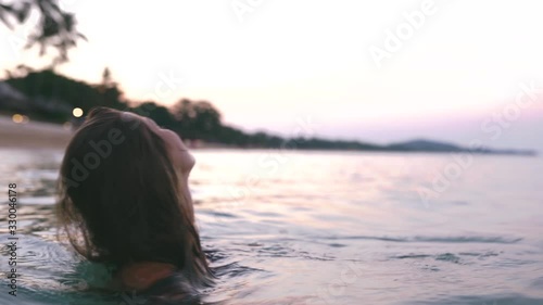 Beautiful slim and young girl swims in the turquoise sea. Long hair and a slender figure in the model. A woman dives under water and splashes. The concept of calm, happiness and relaxation.