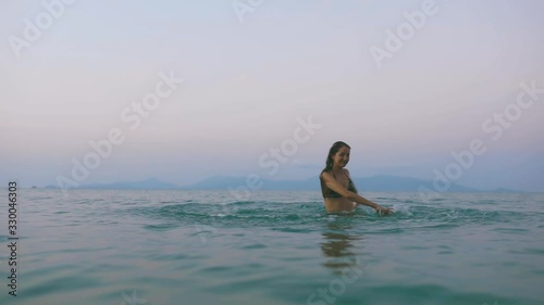 Beautiful slim and young girl swims in the turquoise sea. Long hair and a slender figure in the model. A woman dives under water and splashes. The concept of calm, happiness and relaxation.