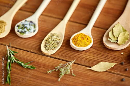 Fototapeta Naklejka Na Ścianę i Meble -  food, culinary and unhealthy eating concept - spoons with different spices and salt on wooden table