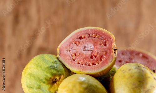 fresh yellow guavas and broken in glass bowl on neutral background