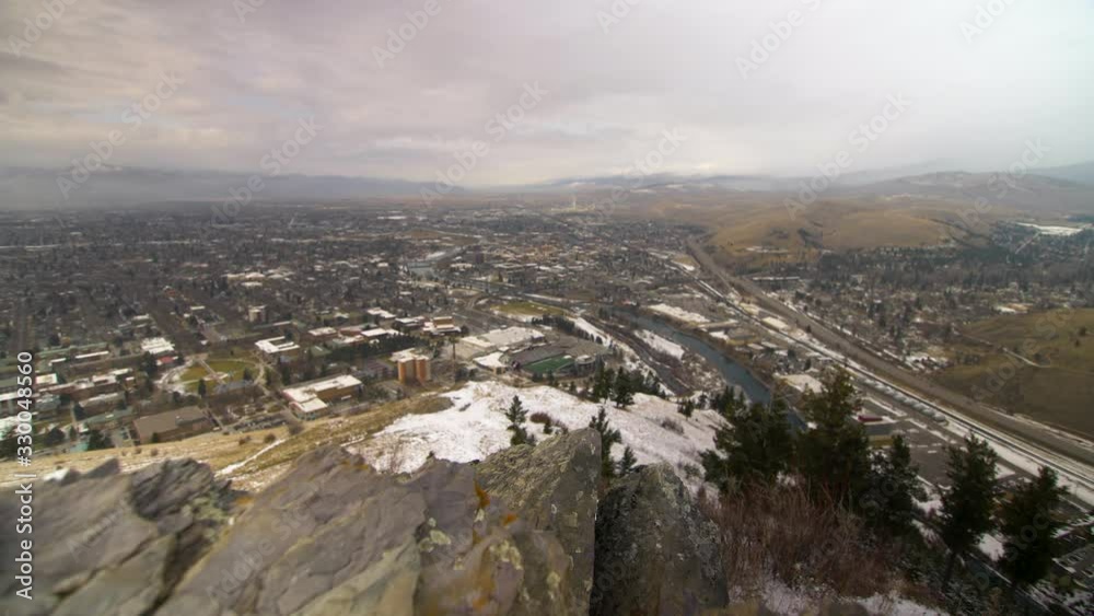 Slider shot moving right to left looking out over Missoula, Montana. Overcast sky. Snow down in valley below. Rock outcropping in focus in foreground. Slider shot moving right to left looking out over Missoula, Montana. Overcast sky. Snow down in valley below. Rock outcropping in focus in foreground.