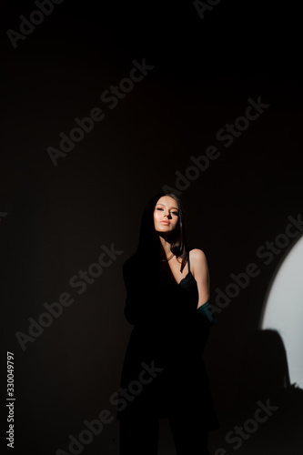 Studio photo of pretty brunette woman in twilight in bra looks into the distance